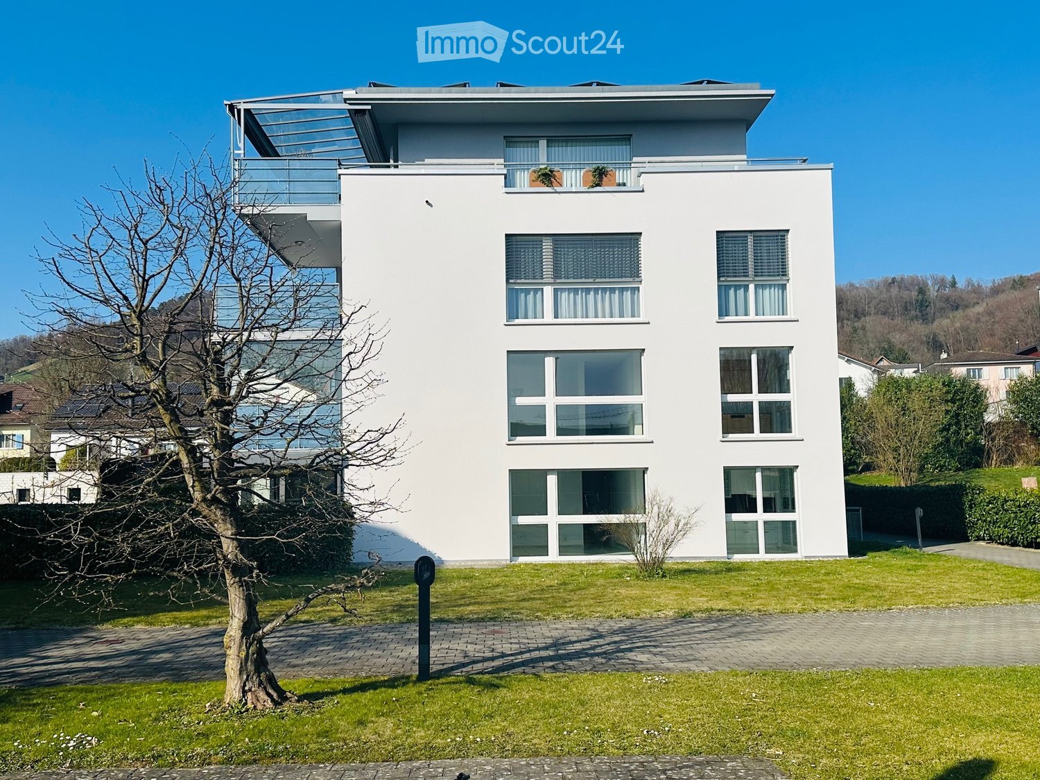 modern white house, 3 floors, large windows, balcony on the top floor, solar panels on the roof