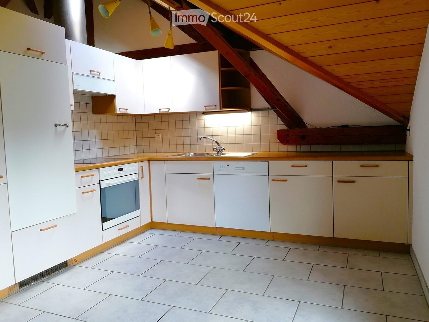 Modern kitchen with white cabinets, wooden accents, tiled walls, and a stainless steel sink and faucet.