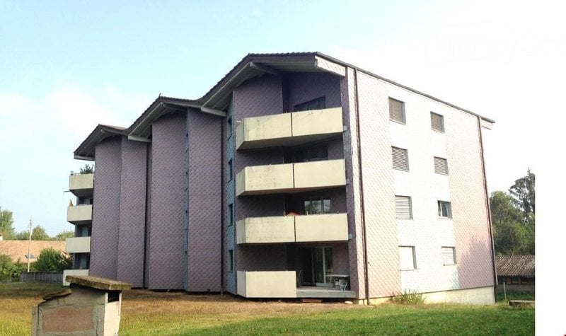 Multi-story residential building with balconies and a mix of purple and white facades.