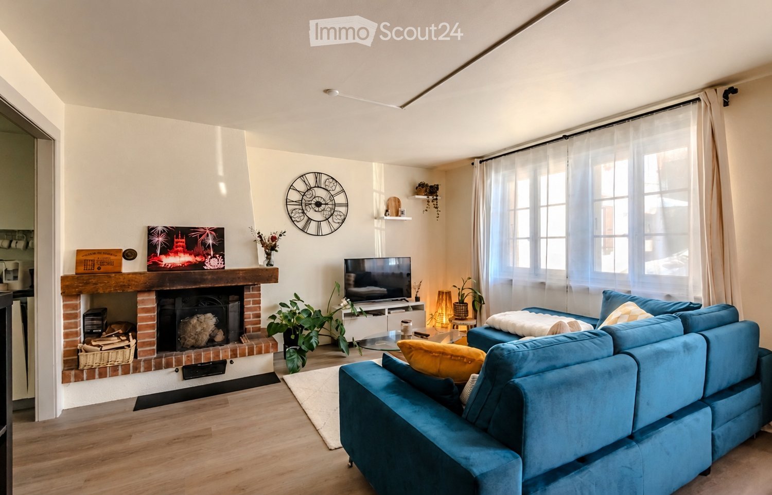 Modern living room with a blue sectional sofa, fireplace, television, coffee table, floor lamp, and decorative items.