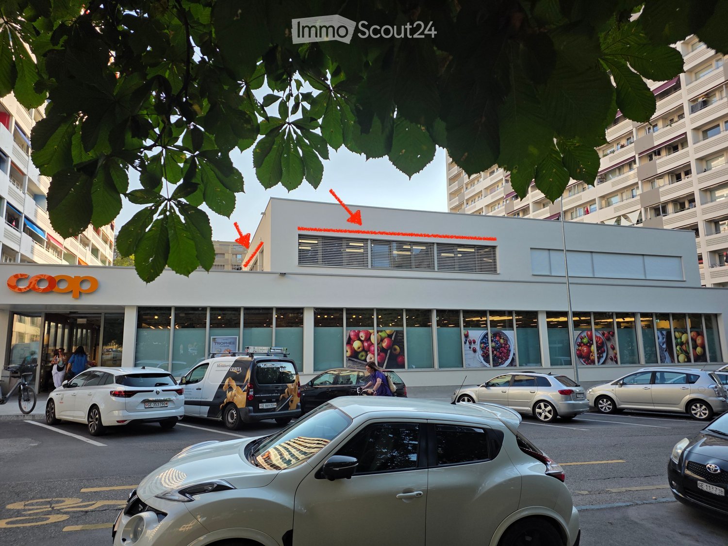 Modern building with large windows and a 'coop' sign, surrounded by parked cars and pedestrians.