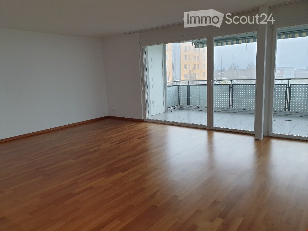 Empty room with wooden flooring and large sliding glass doors leading to a balcony.