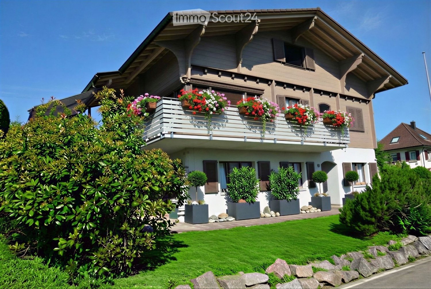 Two-story house with a balcony, flower boxes, and well-maintained garden.