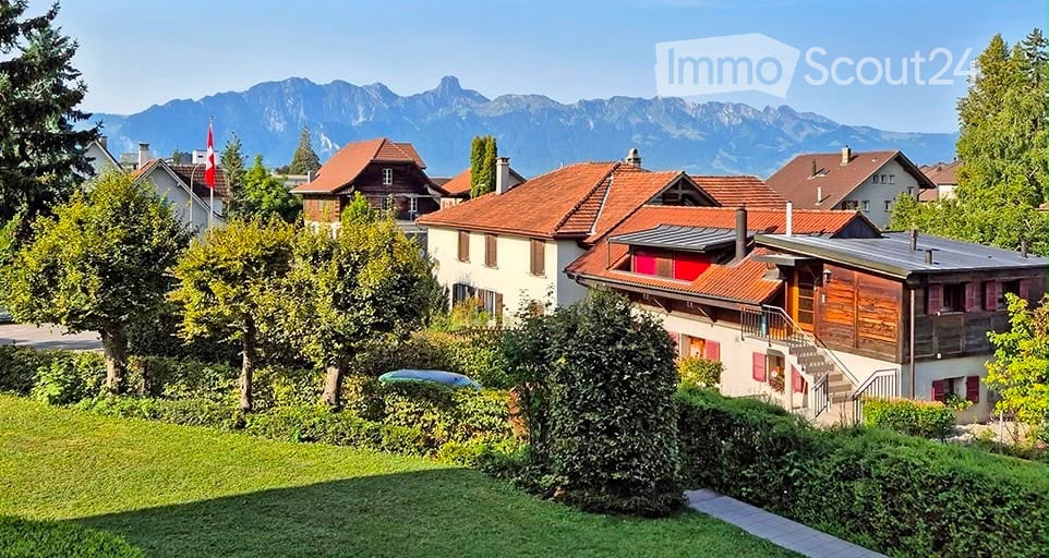 Residential neighborhood with multiple houses, red-tiled roofs, and a scenic mountain view in the background.