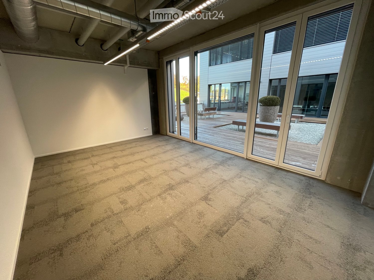 Empty room with carpeted floor, large glass sliding doors leading to an outdoor deck area.