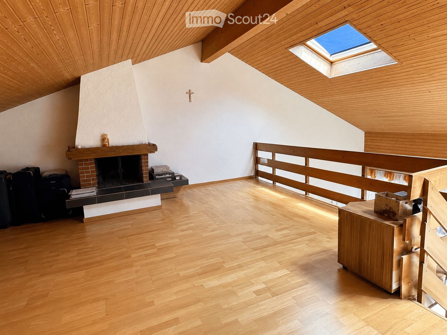 Bright, wooden-floored room with a fireplace, wooden bench, and a small table with suitcases.