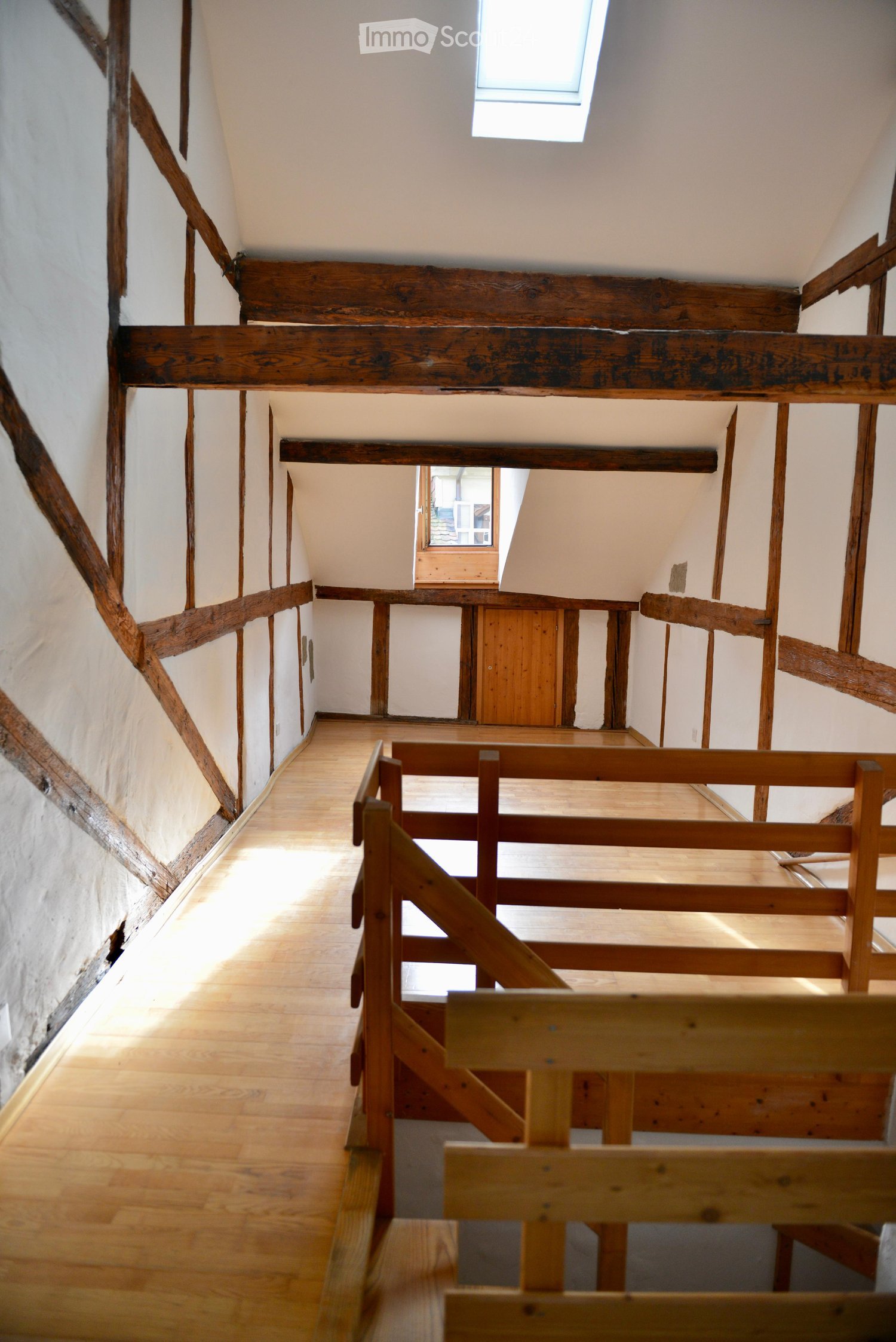 Exposed wooden beams, white walls, wooden staircase, wooden floor, small window