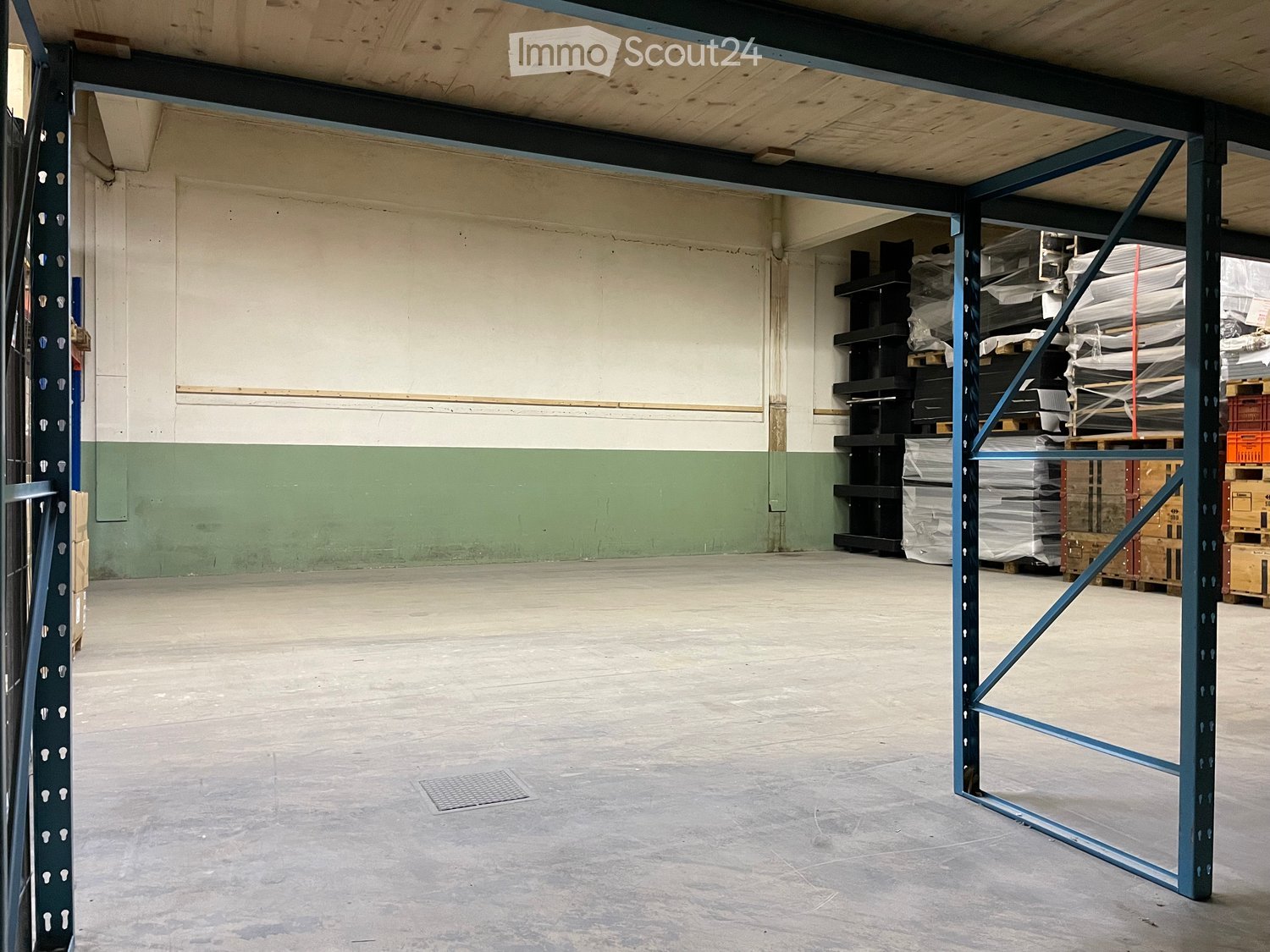 Empty warehouse space with concrete floor, metal shelving units, and storage crates in the background.