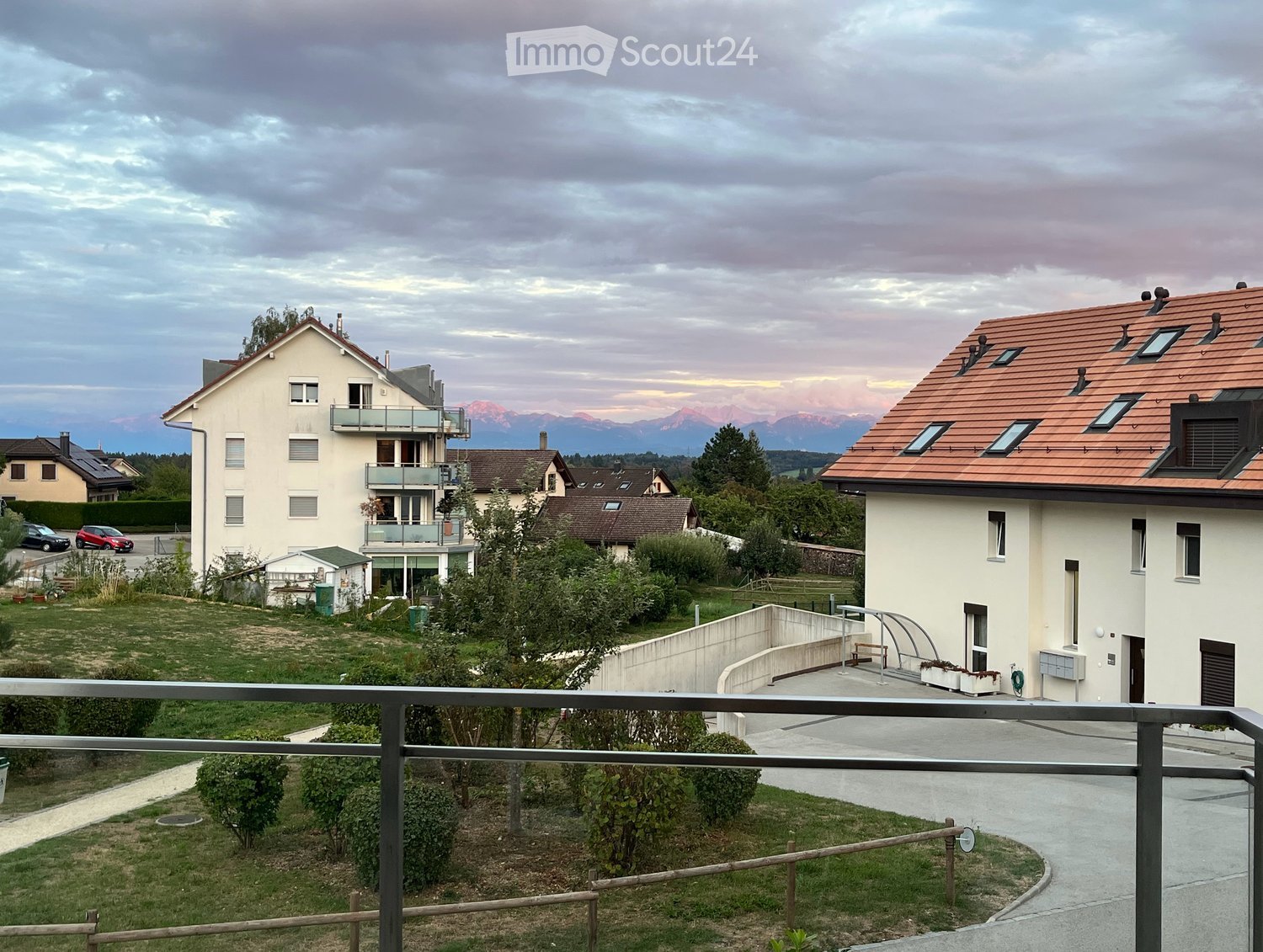 Residential area with multiple houses, a balcony, and a scenic mountain view in the background.