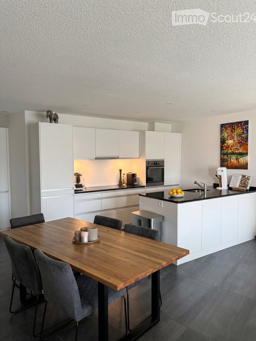 Modern kitchen with white cabinets, a wooden dining table, grey chairs, and a black countertop with a sink, faucet, and various appliances.
