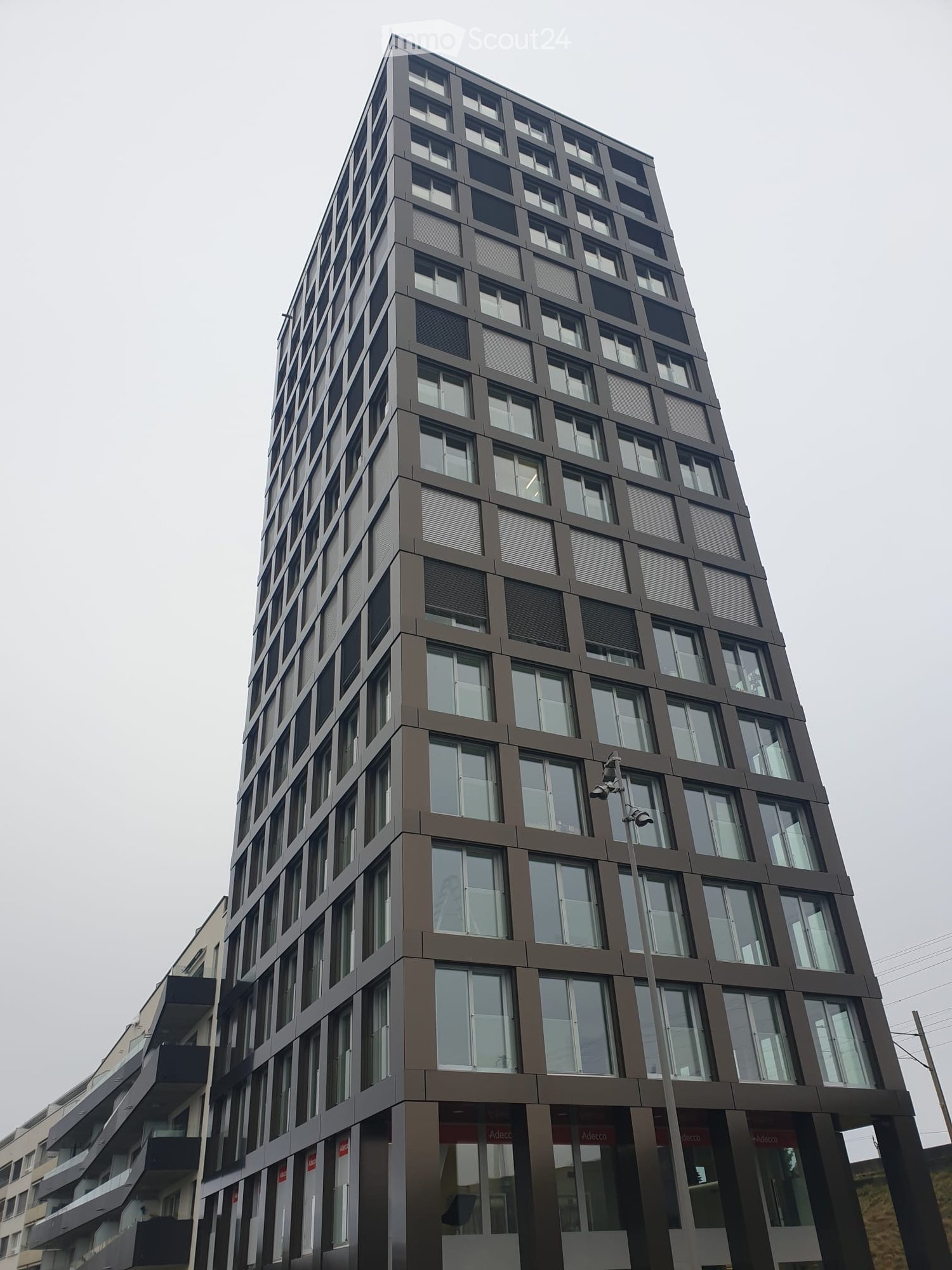 Modern multi-story building with a sleek, contemporary design featuring large windows and a grid-like facade pattern.