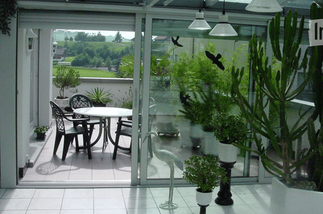 glass sliding doors, balcony, table and chairs, potted plants, decorative bird statue, tiled floor