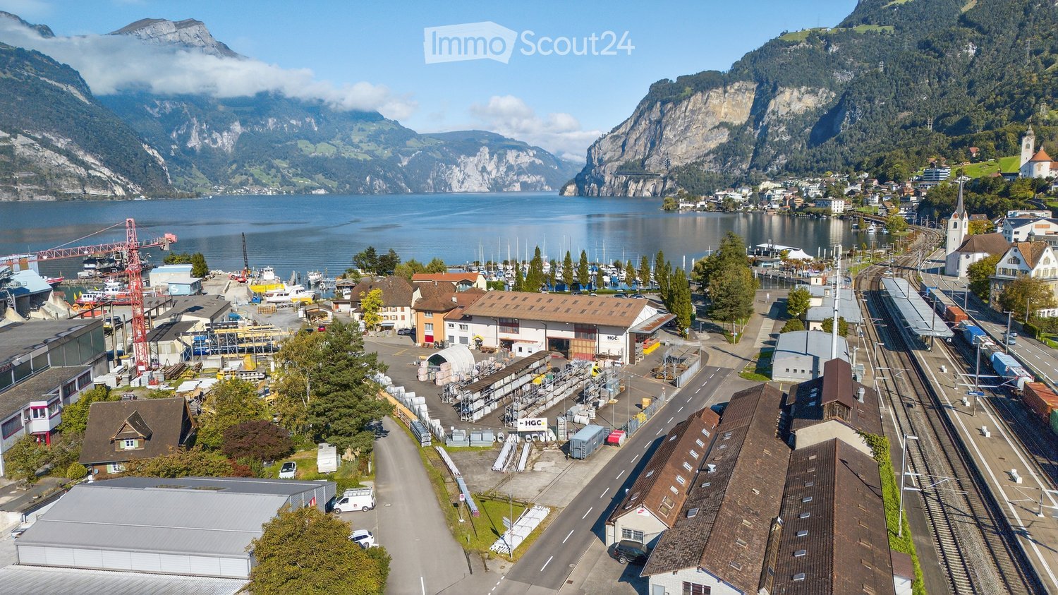 aerial view of an industrial area near a lake and a river with mountains in the background