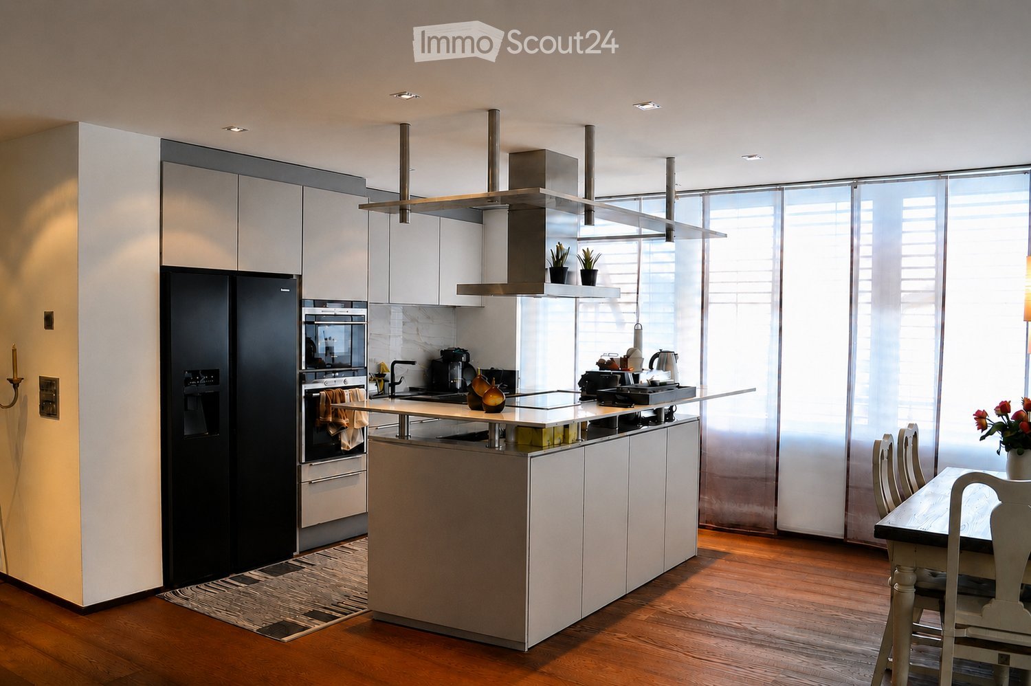 Modern kitchen with white cabinets, stainless steel appliances, island, and dining area with a table and chairs.