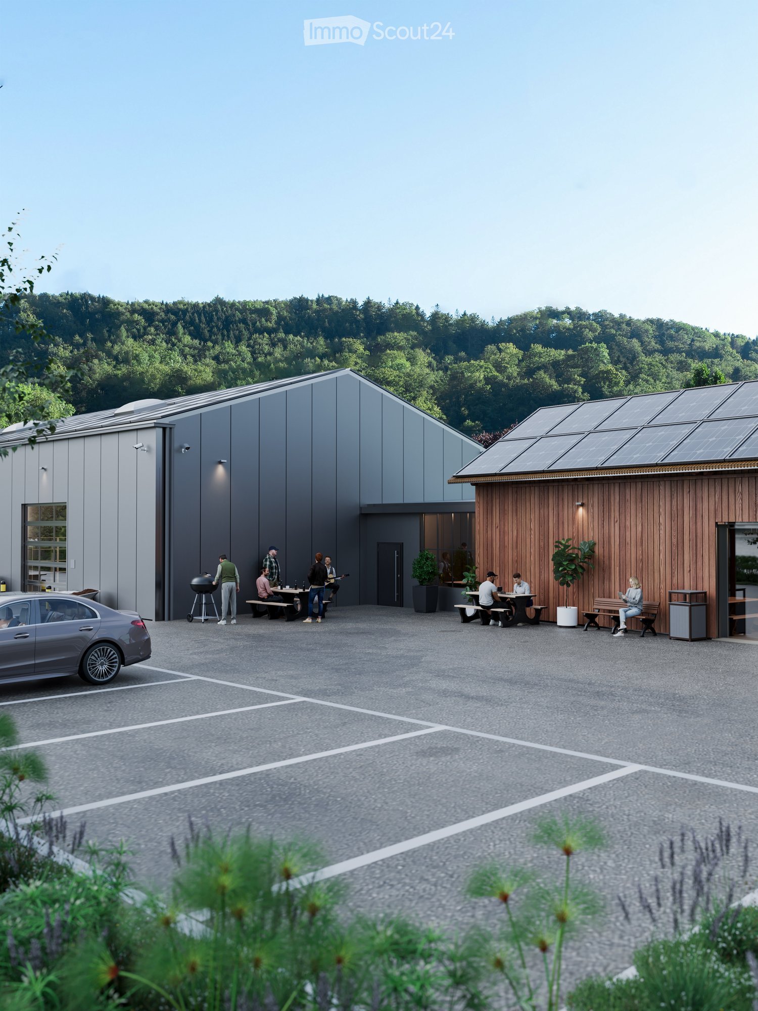 Outdoor area with modern buildings, seating areas, and people gathered around tables and benches. Solar panels on the roof of one building.