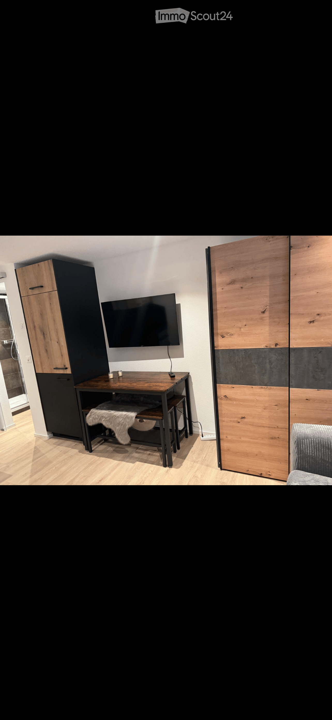 A room with a table, sofa, cabinets, TV, and wooden flooring