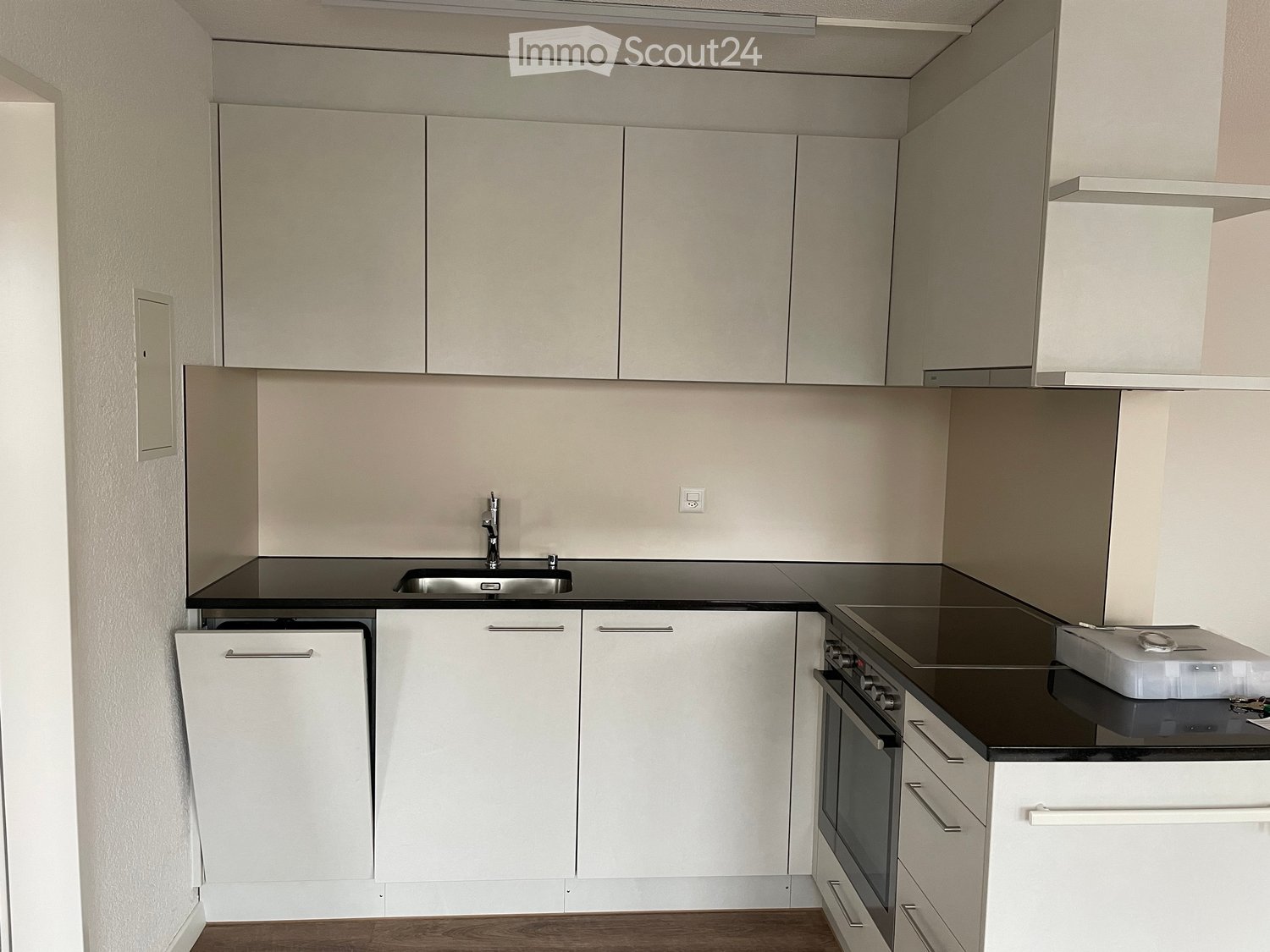 Modern kitchen with white cabinets, black countertops, a sink, and an oven.