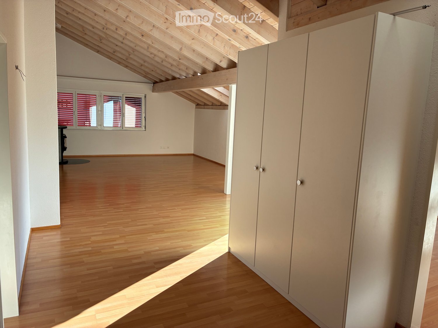 empty room, wooden floor, tall ceiling, three large windows, large white wardrobe