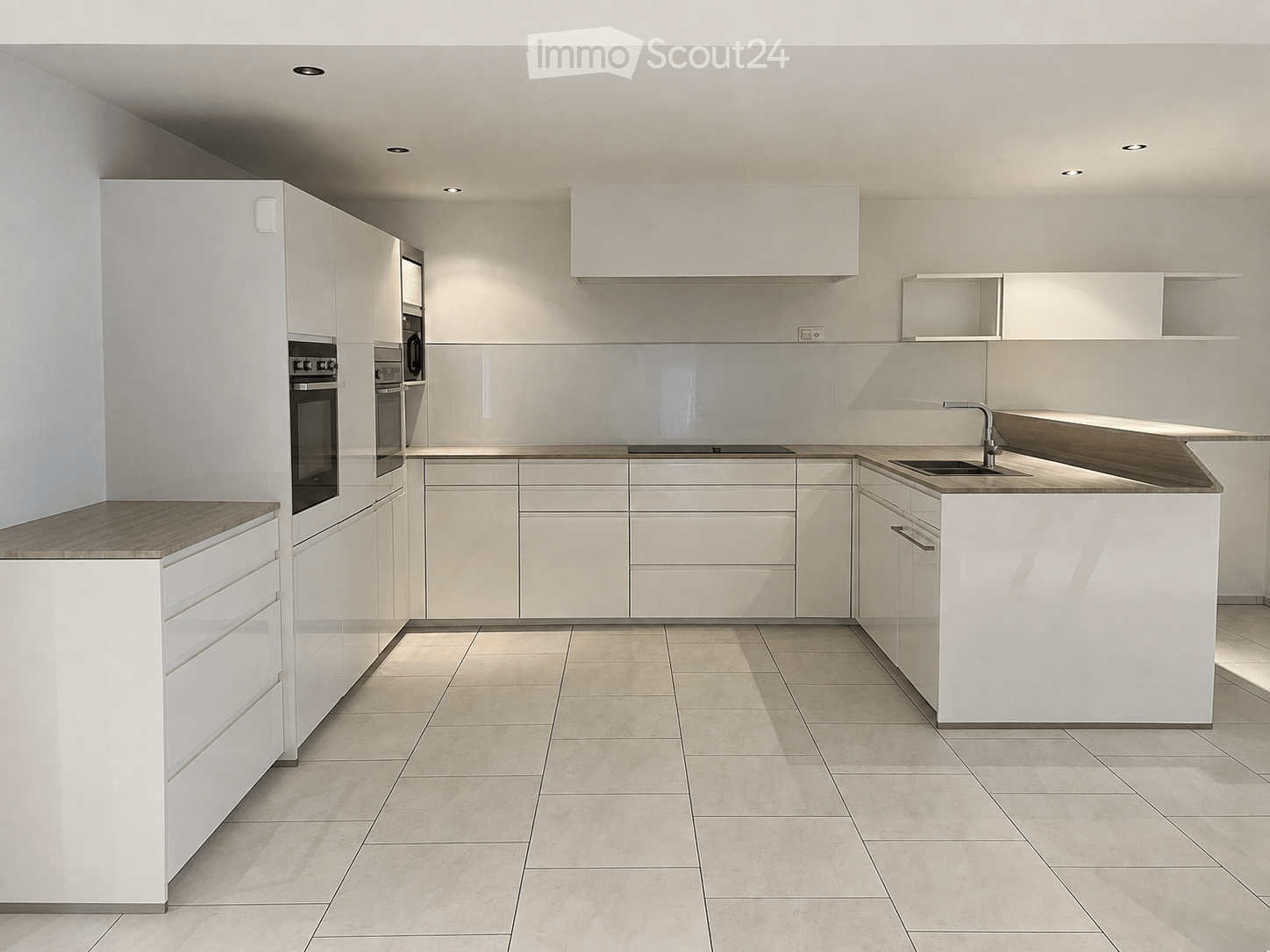 Modern kitchen with white cabinets, wooden countertops, and built-in appliances including an oven and sink.