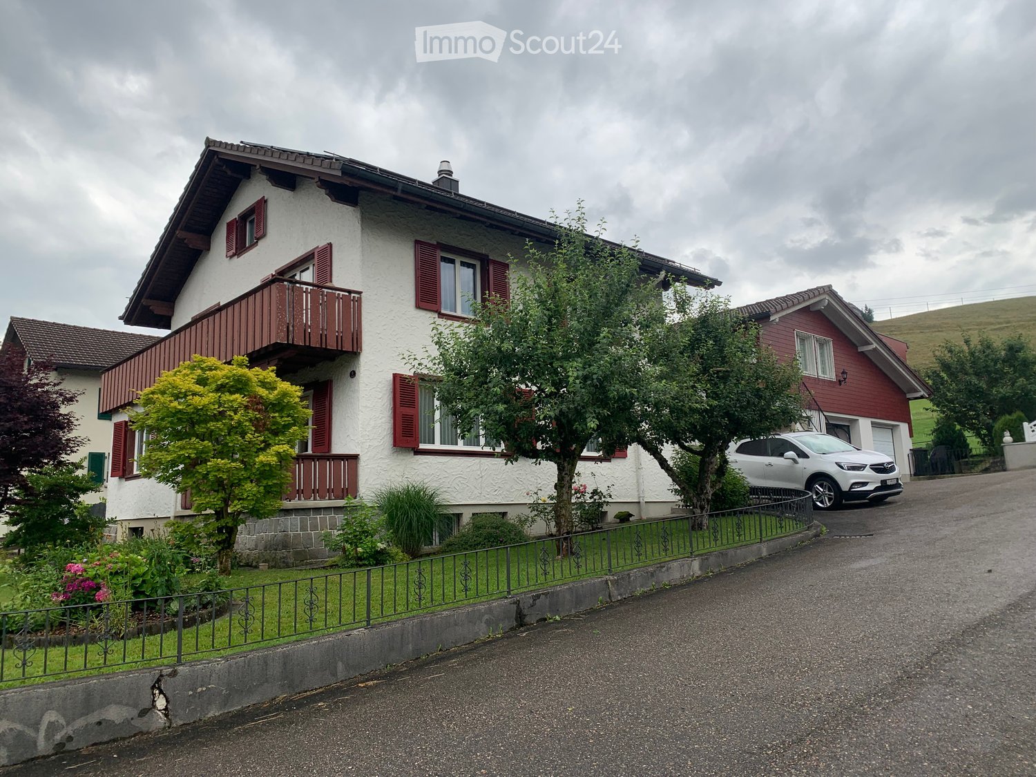 2 story house, white exterior, red shutters, balcony, driveway, parked car
