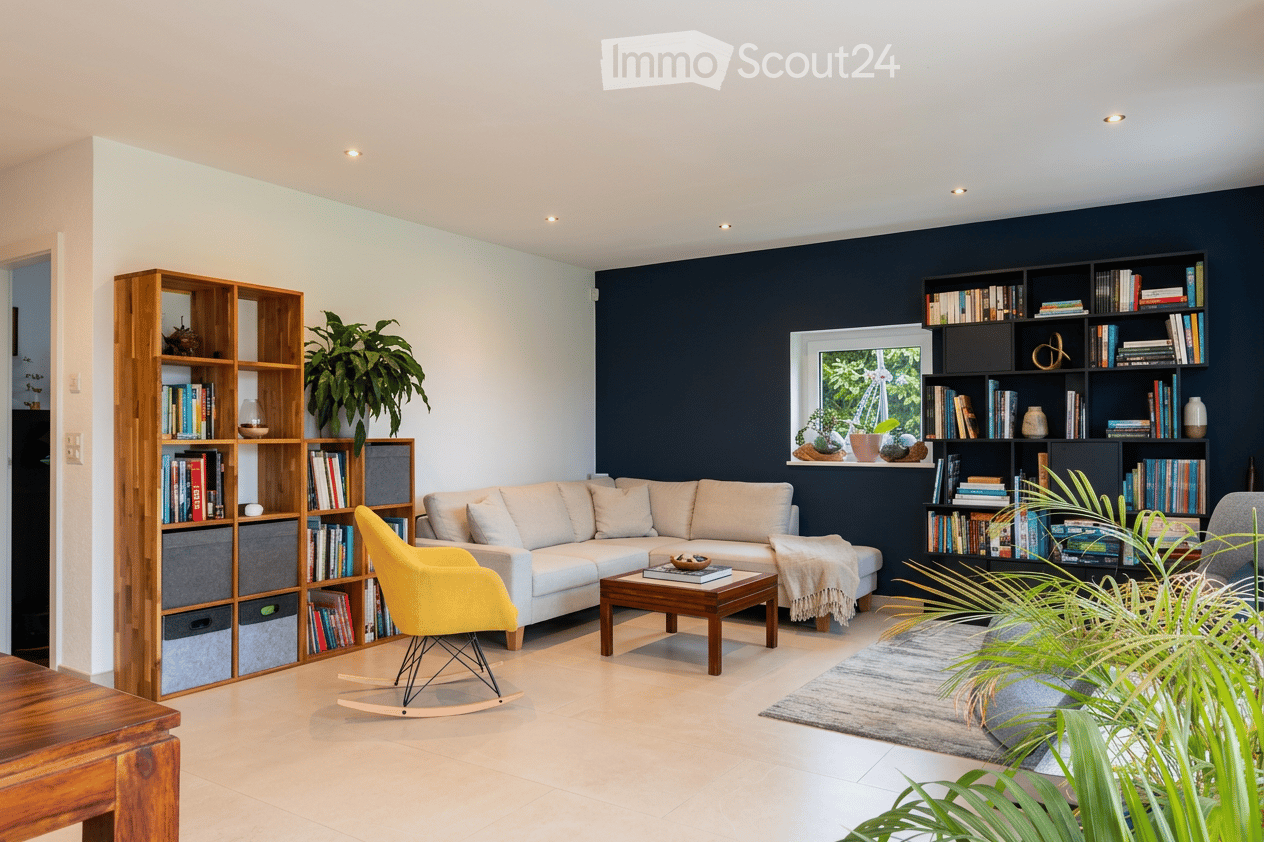 Modern living room with a white sectional sofa, wooden coffee table, yellow armchair, bookshelf, and decorative plants.