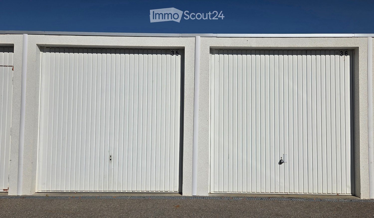 Two white garage doors with vertical slats and numbers3.5 and 3.6 on the wall above them.