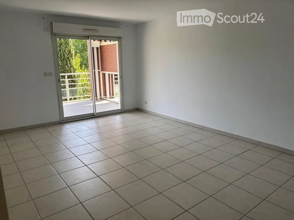 Empty room with tiled floor, white walls, and a sliding glass door leading to a balcony.