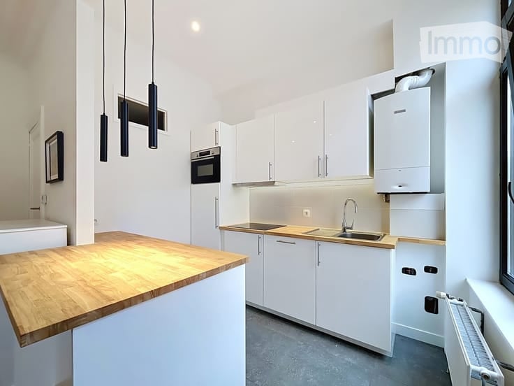 Modern kitchen with white cabinets, wooden countertop, stainless steel sink, and built-in oven.