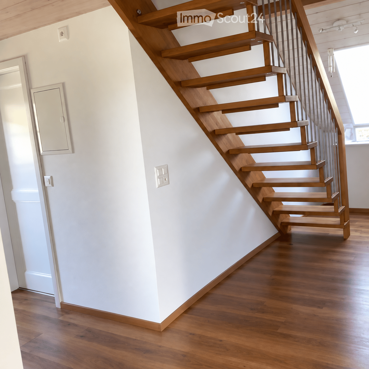 Wooden staircase with metal railing, white walls, and wooden flooring.