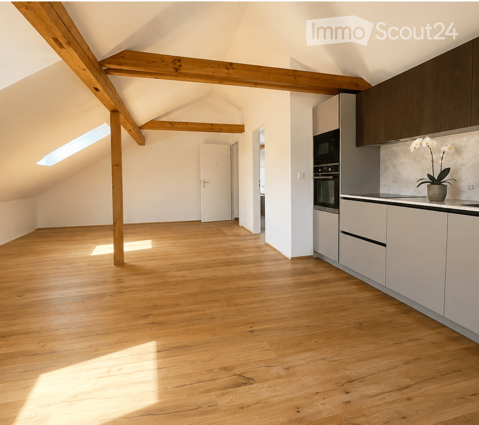 Bright, open attic space with wooden beams and hardwood flooring, featuring a small kitchen area with modern cabinets and appliances.