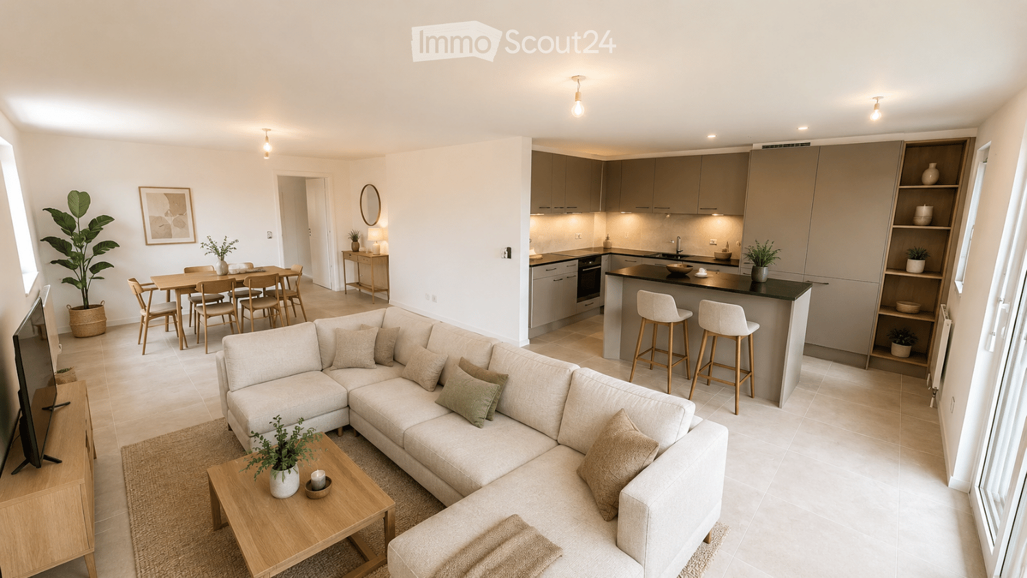 Open-plan living and dining area with a sectional sofa, coffee table, dining table with chairs, kitchen with island and bar stools, and decorative plants.