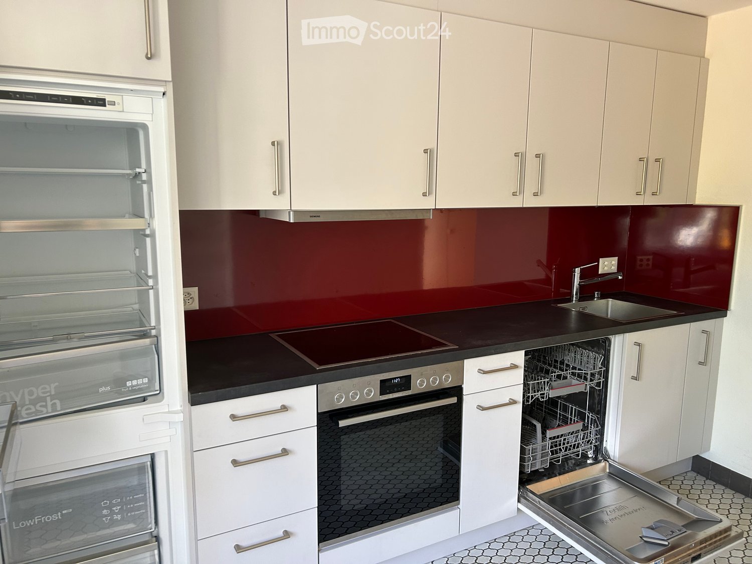 Modern kitchen with white cabinets, stainless steel appliances, and a dark countertop.