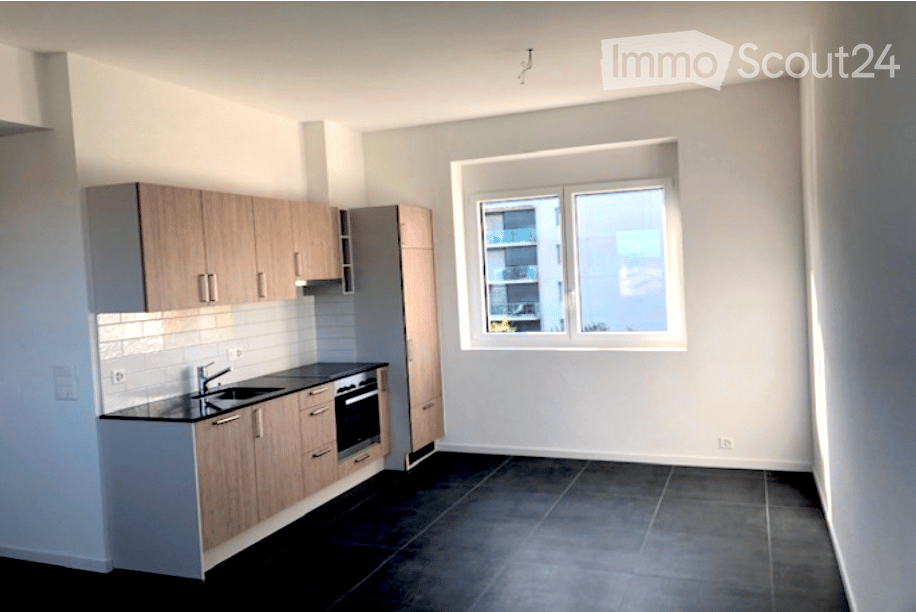 Modern kitchen with light wood cabinets, black countertops, and a large window overlooking a cityscape.
