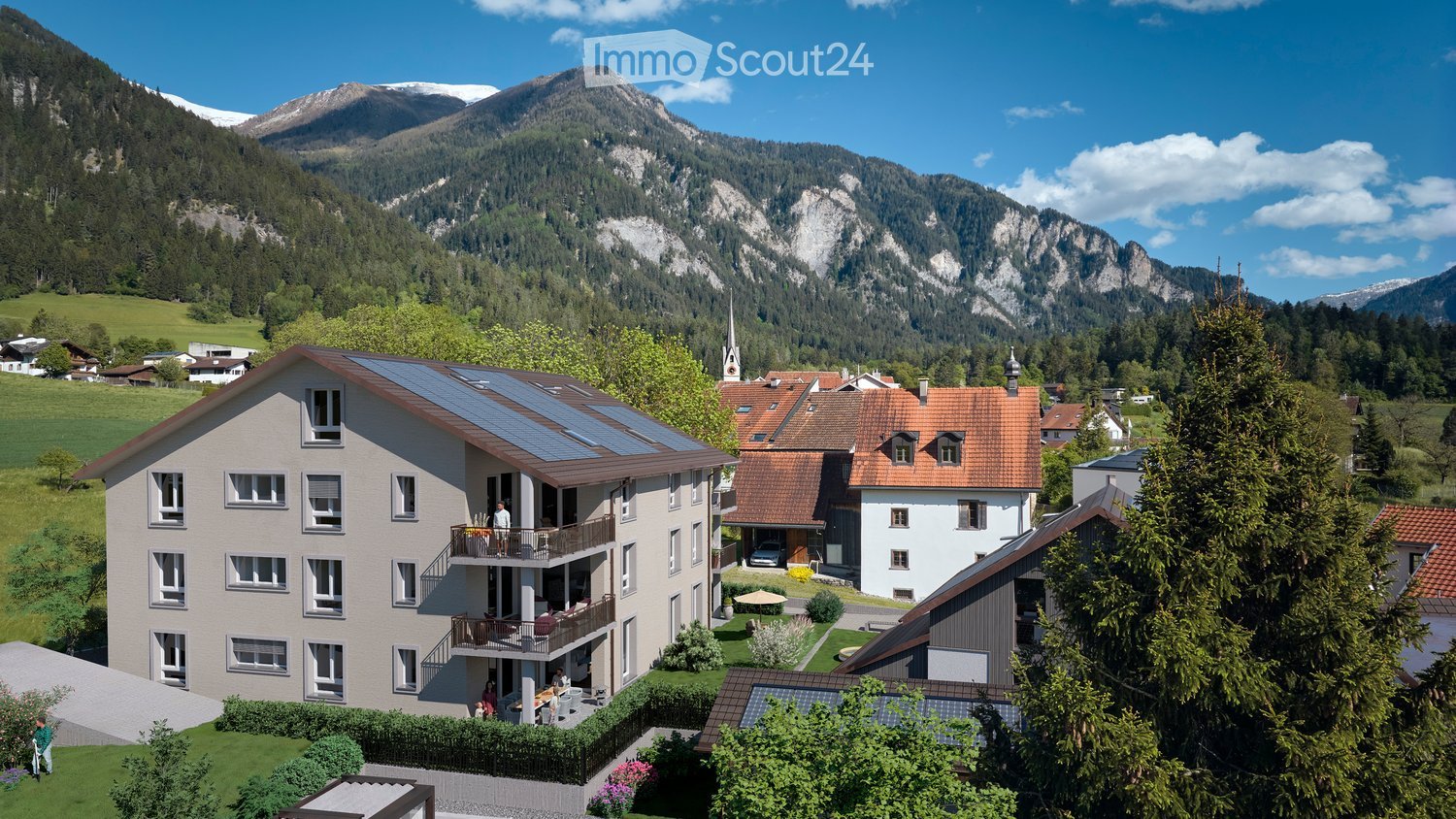 A two-story house with solar panels on the roof, surrounded by greenery and mountains in the background. The house features multiple windows and balconies.