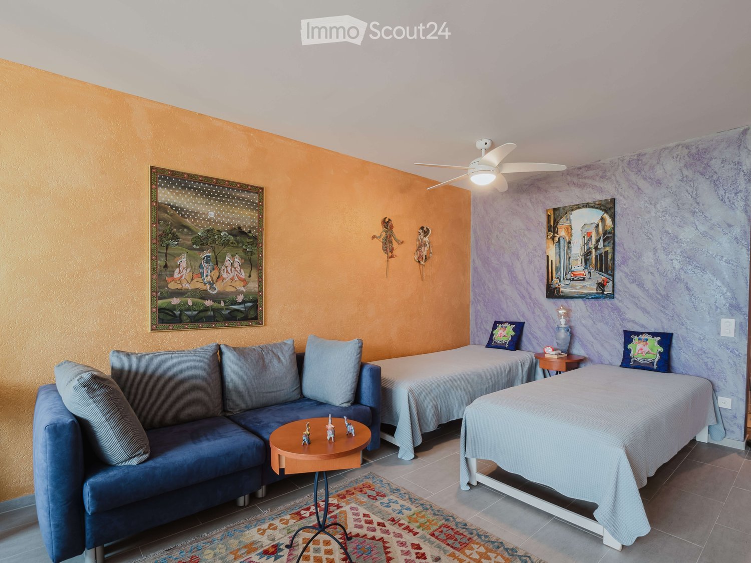 Cozy room with two single beds, a sofa, a small round table, nightstands, and decorative items including vases and artwork.