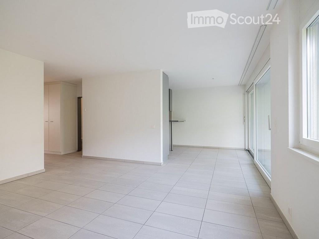 Empty room with white walls, tiled floor, and large windows. No furniture or equipment present.