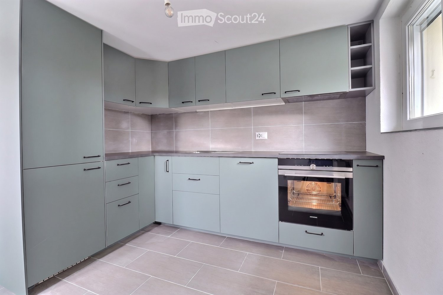 Modern kitchen with light blue cabinets, stainless steel oven, and tiled backsplash.