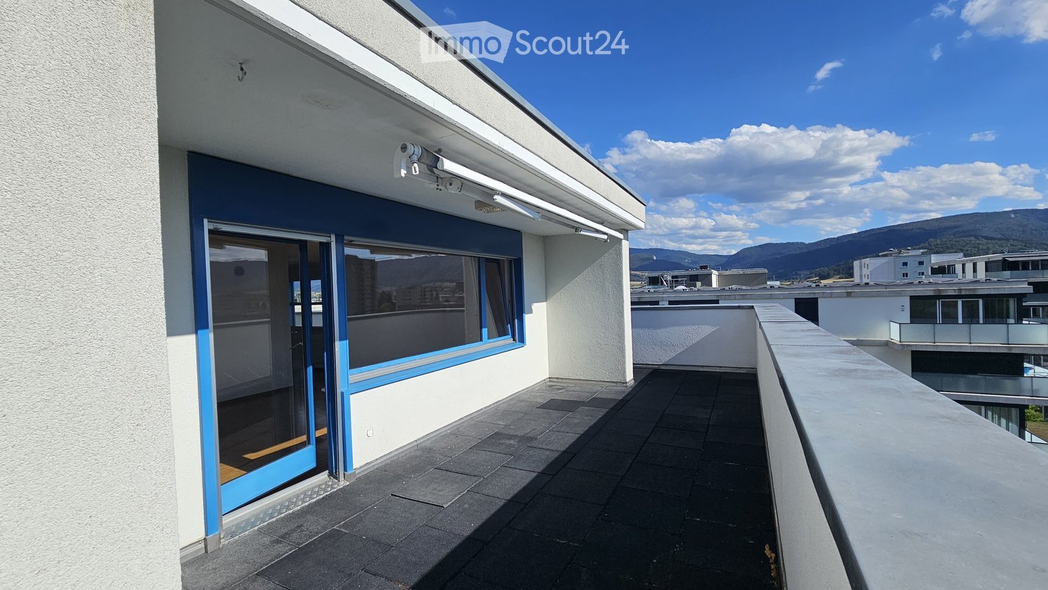 Balcony with dark tiled flooring, glass door leading inside, white walls, and a scenic mountain view.