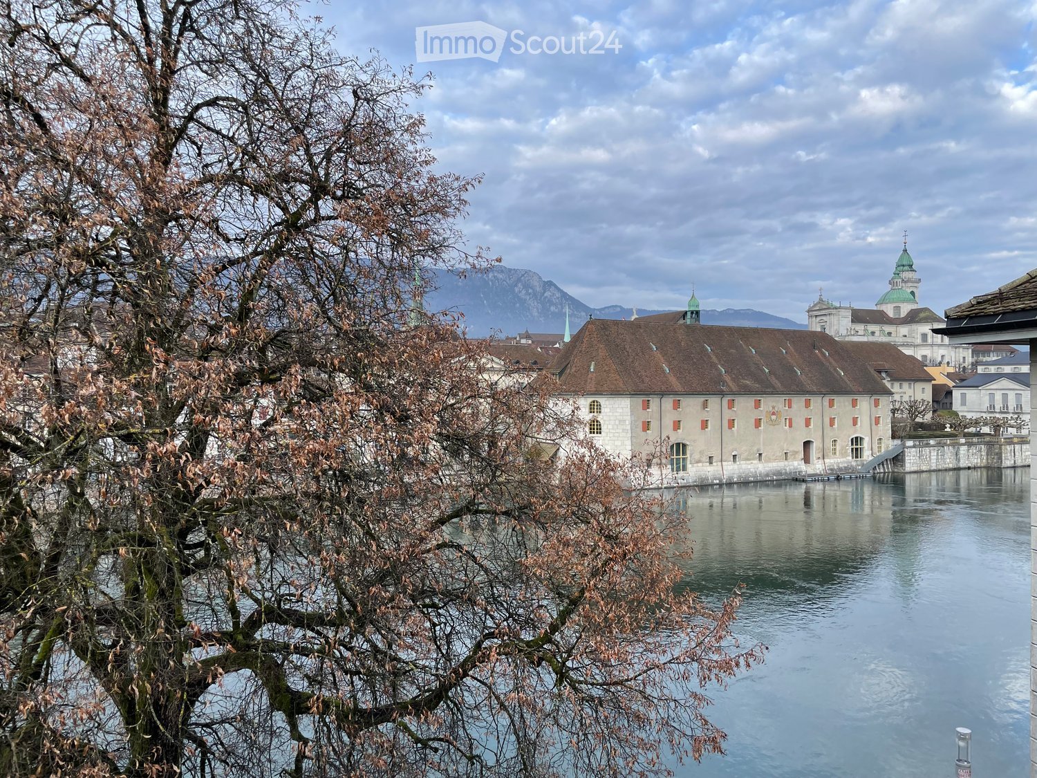 Building on the side of the water with mountains in the background.