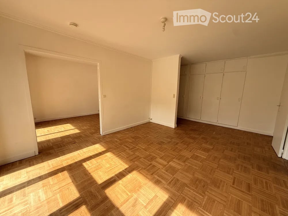 Empty room with wooden parquet flooring, white walls, and built-in wardrobes. No furniture or equipment present.