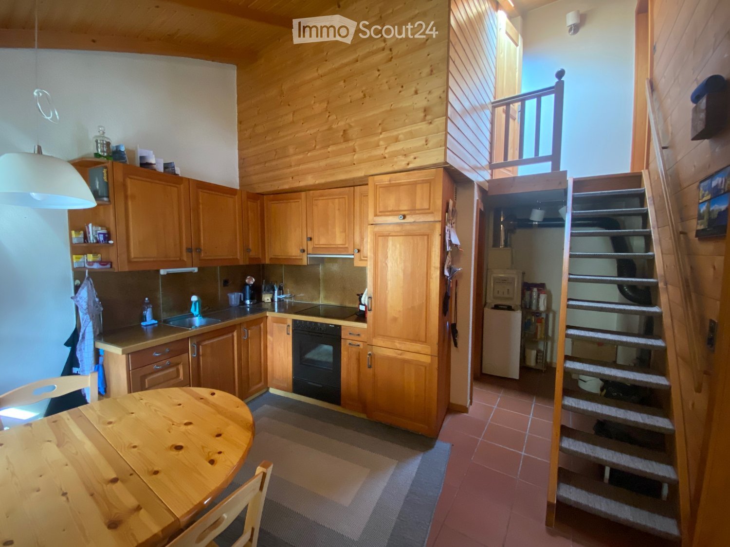 Kitchen with wooden cabinets, wooden table, round chairs, stainless steel appliances
