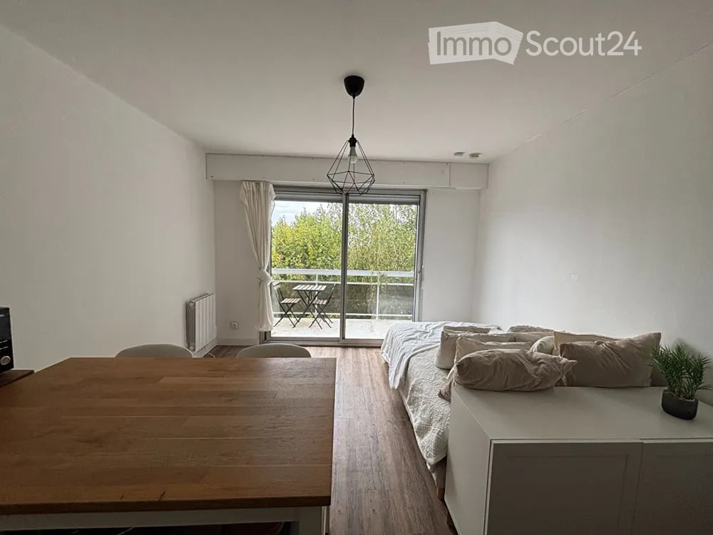 Cozy studio with a bed, sofa, dining table, chairs, and a small balcony with outdoor furniture.