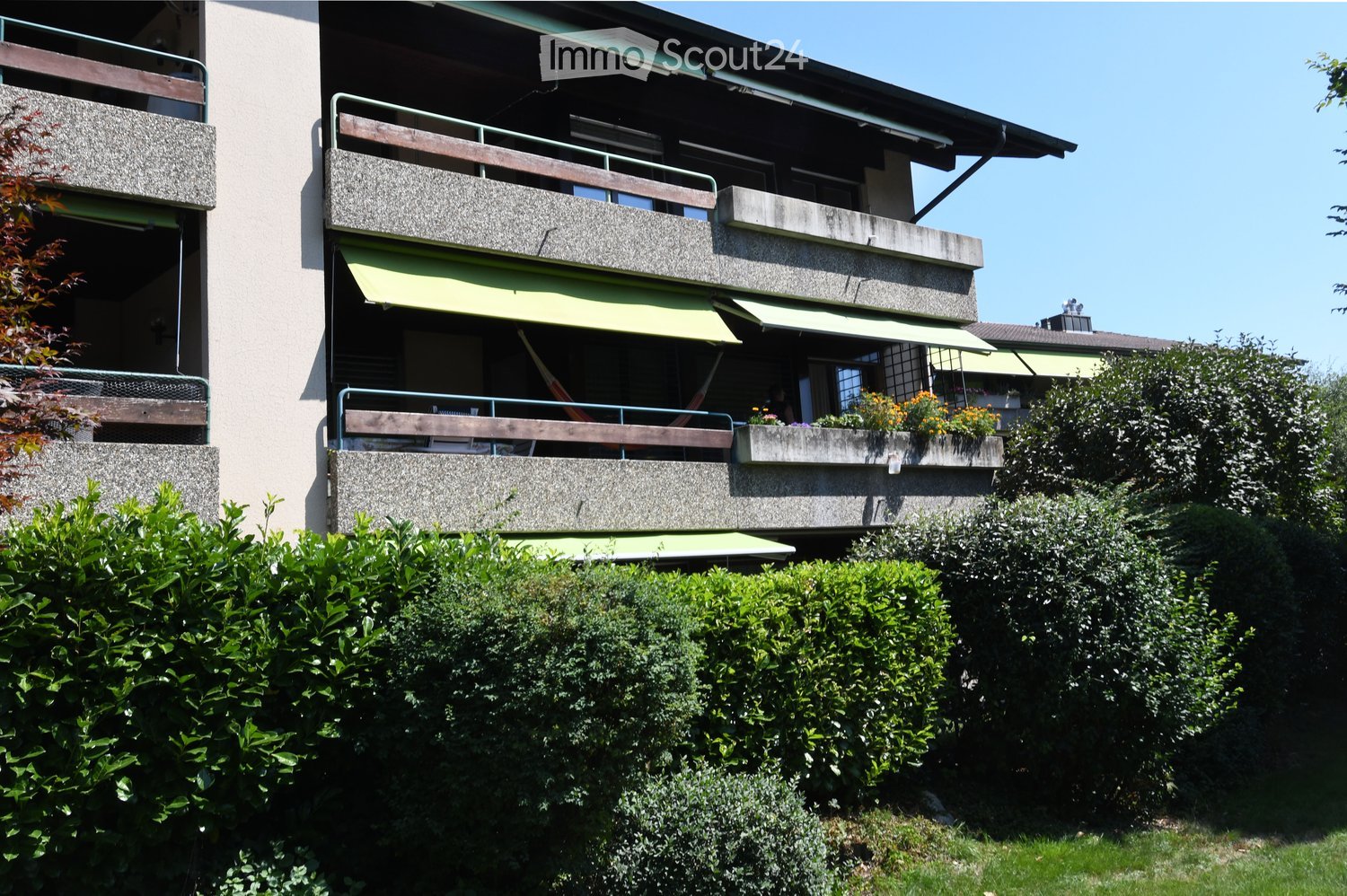 multiple balconies, awnings, windows, garden with hedges