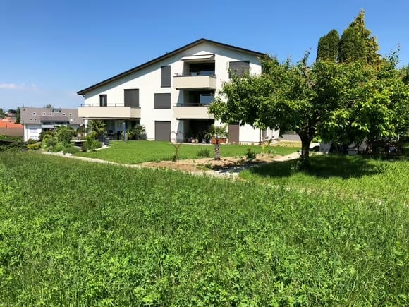 Modern two-story house with white exterior, multiple balconies, and a well-maintained garden area.