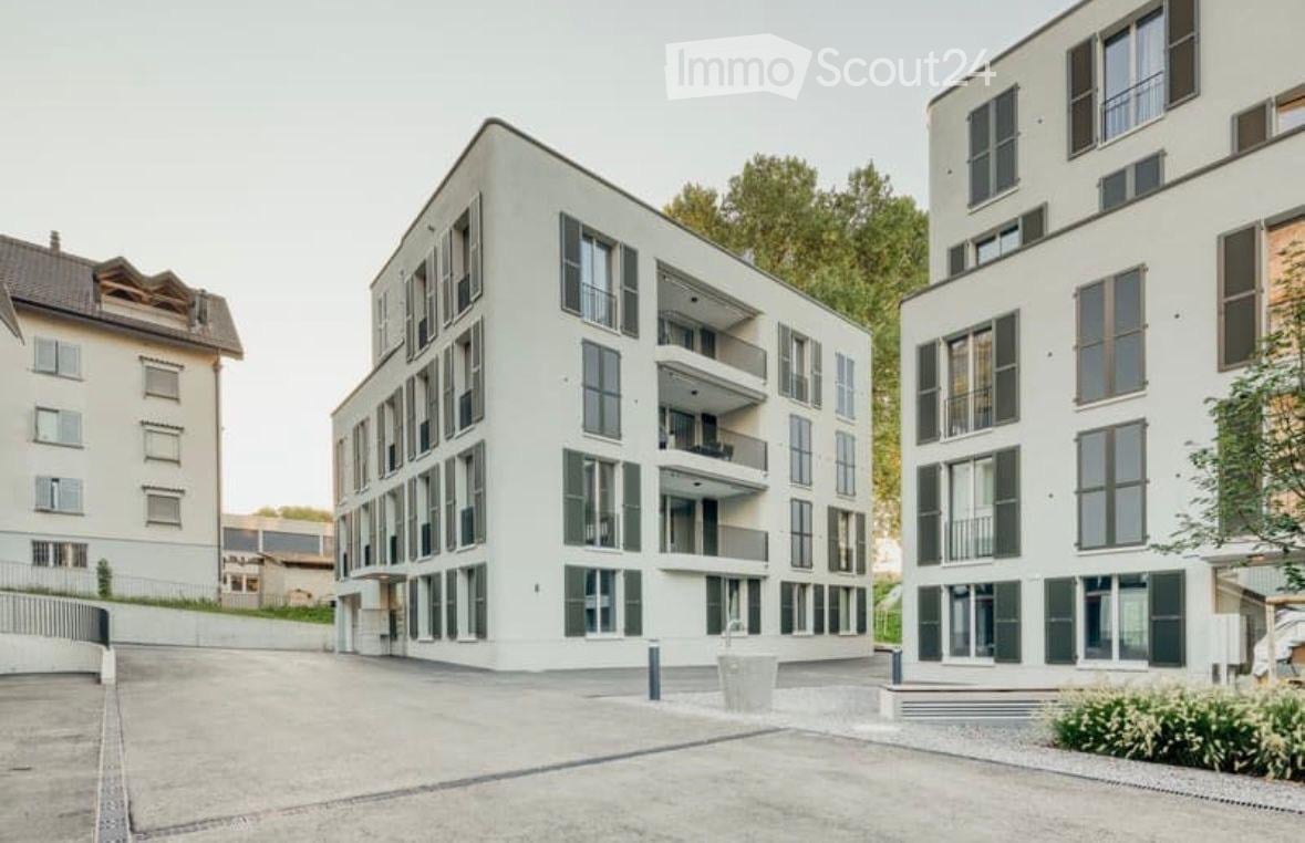 Modern multi-story residential building with white facade, large windows, and balconies.