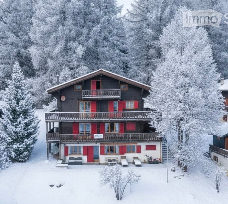 Detached house in a snowy landscape with balconies and red shutters