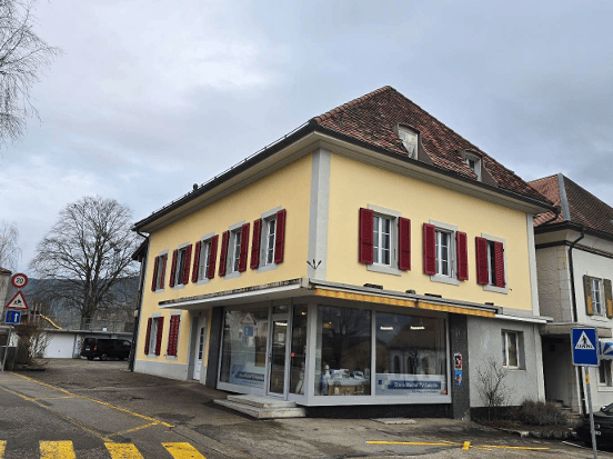 2 story building, yellow exterior, red shutters, glass storefront, parking lot