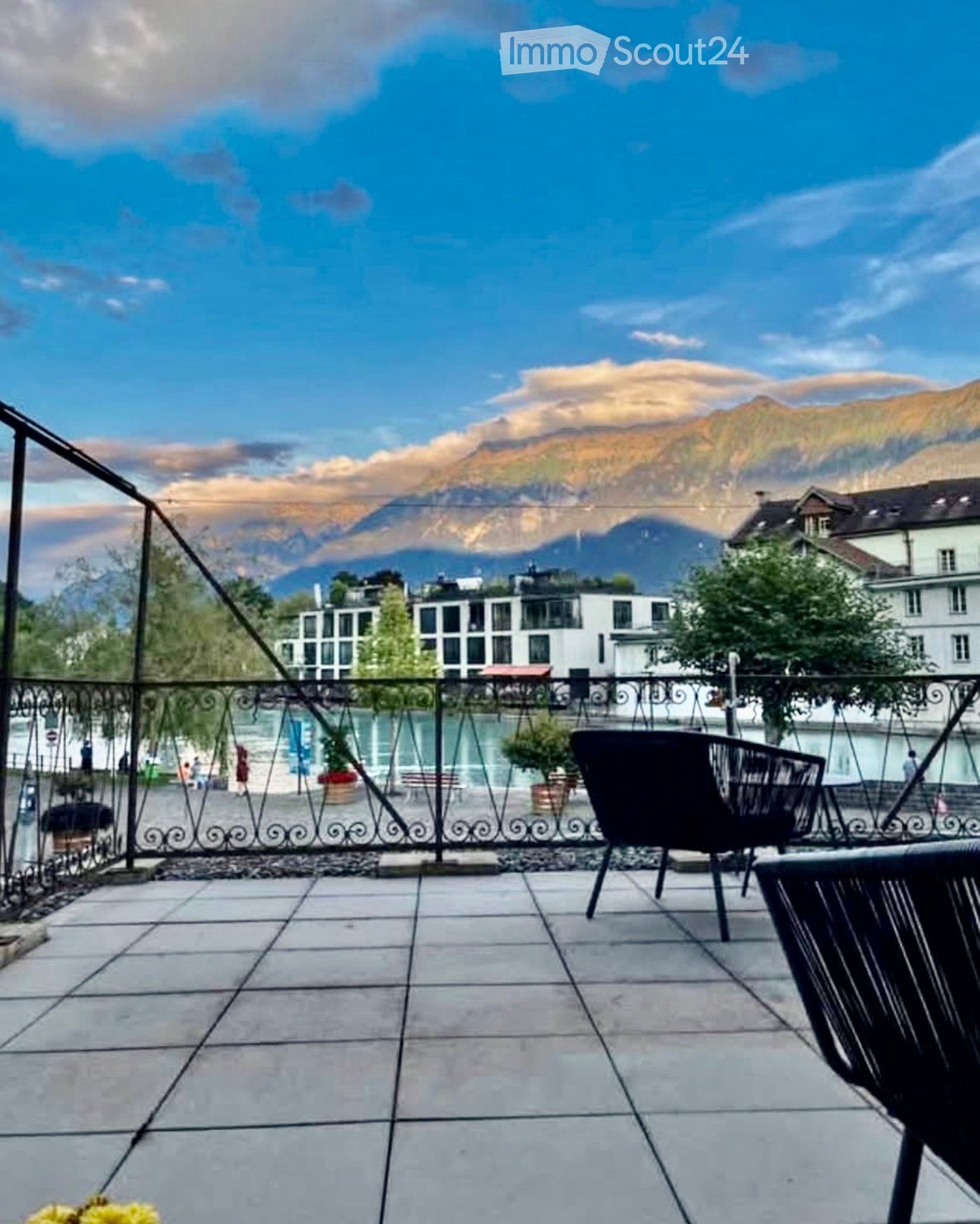 Balcony with tiled floor, metal railing, and scenic mountain view in the background.