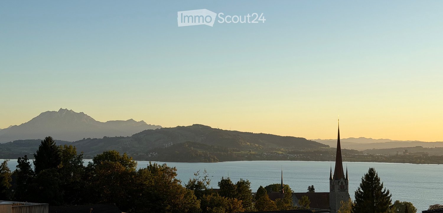 Scenic view of a lake with a church spire and mountains in the background.