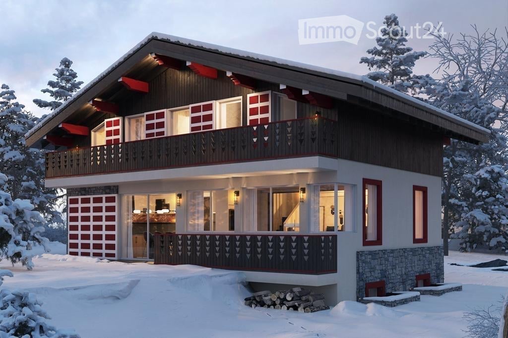 Two-story wooden house with red and white accents, large windows, and a garage, surrounded by snow-covered trees.